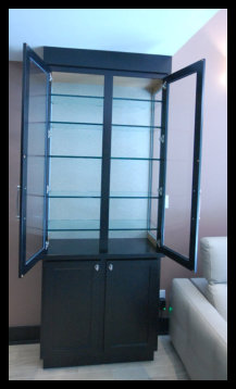 Interior view of a custom freestanding display cabinet showing open double doors and premium half-inch thick glass shelving.