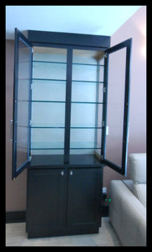 Interior view of a custom freestanding display cabinet showing open double doors and premium half-inch thick glass shelving.