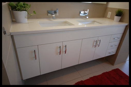 Handcrafted white floating vanity installation showing custom cabinetry layout with high-end drawer glides and integrated double sink top.