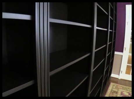 Modern black-on-black built-in featuring precision 3-inch triple fluted moldings and adjustable shelving with a sleek, reflective clear coat finish.