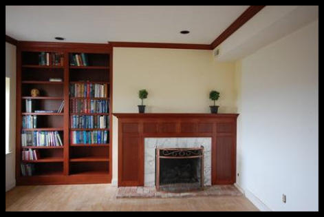 Custom floor-to-ceiling Sapele hard wood built-in library, including twin bookcases with LED lighting, seamlessly integrated with a matching fireplace mantle and surround paneling.