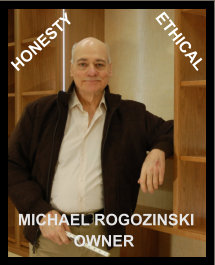 Owner Michael Rogozinski leaning against a cherry wood cabinet with Honesty and Ethical sign above.