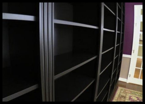 Modern black-on-black built-in featuring precision 3-inch triple fluted moldings and adjustable shelving with a sleek, reflective clear coat finish.