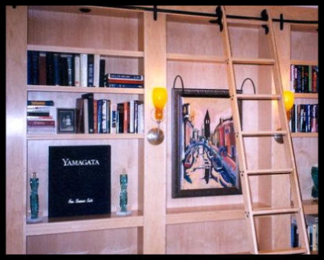 Custom L-shaped maple library built-in; 16-foot span featuring 3-inch and 1.25-inch shelves, 6-inch vertical dividers, 5-inch round sconces, and black rolling ladder hardware.