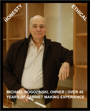 Owner Michael Rogozinski leaning against a cherry wood cabinet with Honesty and Ethical sign above.