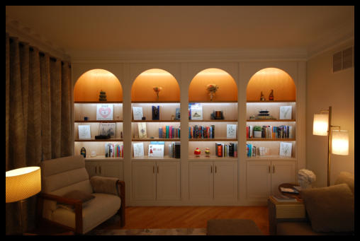 Custom half-circle top oak bookcase built-in with mission-style inset doors and integrated LED lighting, installed in Chalfont, PA.