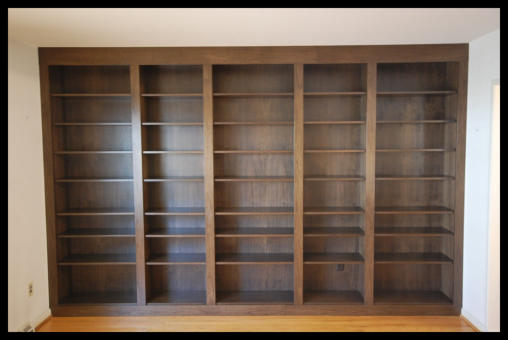 Walnut floor-to-ceiling wall-to-wall built-in bookcases, 5-tier library with 3-inch wide vertical dividers.